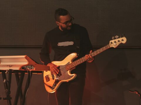 a man standing next to a keyboard and a guitar