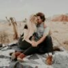 man and woman sitting on blanket while holding each other hands