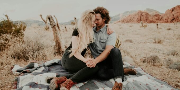 man and woman sitting on blanket while holding each other hands